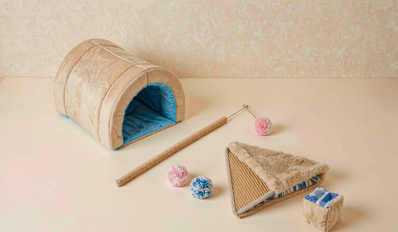 Flat lay of assorted cat toys including plush tunnel, teaser wand and scratching pad