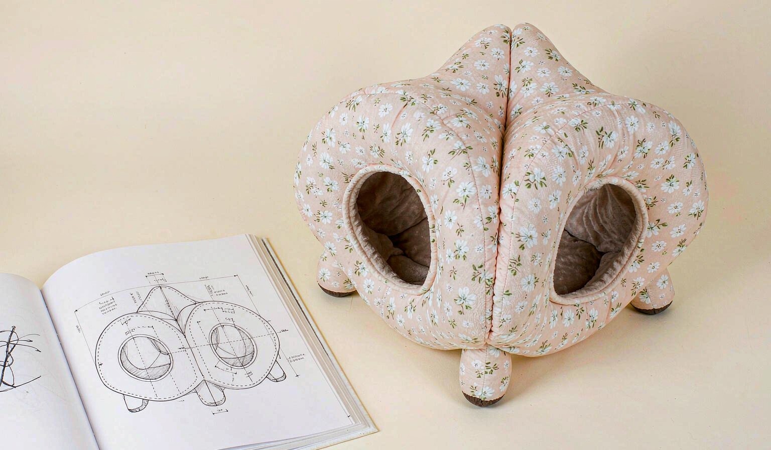 Sketchbook with a pencil drawing of a cat tunnel next to the finished plush product