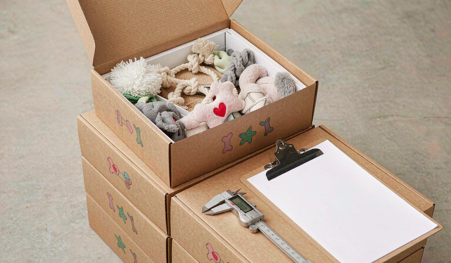Stacked cartons of pet toys with a QC checklist clipboard and measuring caliper